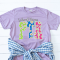 Lavender t-shirt featuring colorful daisy-pattern PTA lettering with optional school name personalization.