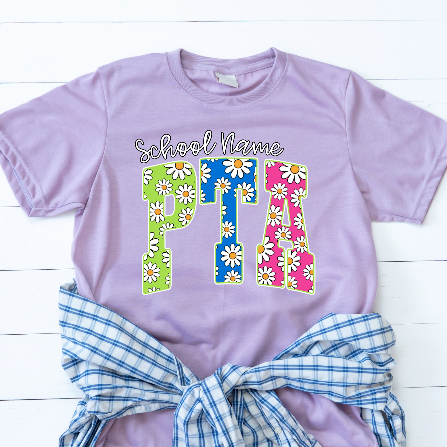 Lavender t-shirt featuring colorful daisy-pattern PTA lettering with optional school name personalization.